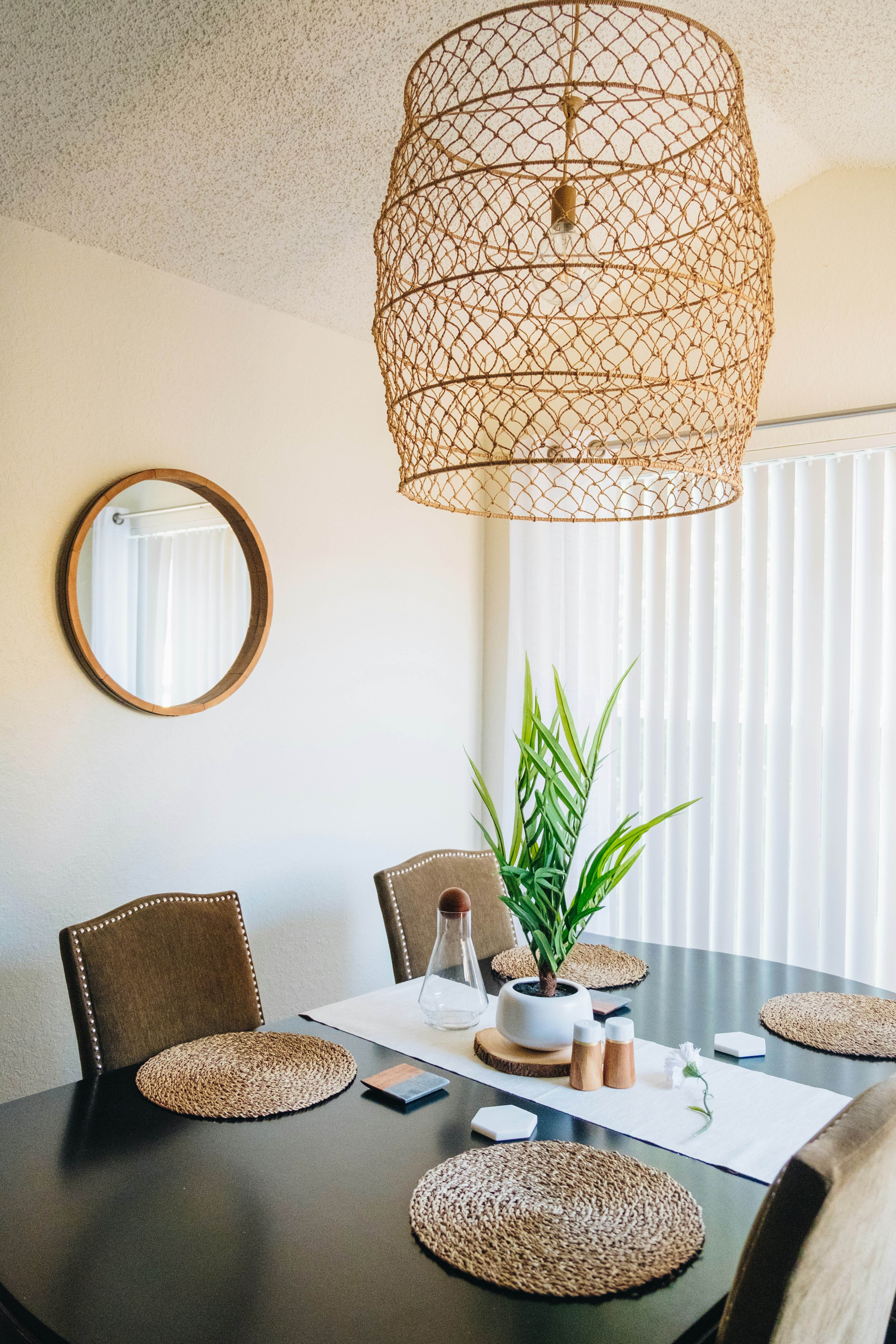 A sunlit boho dining nook with a round table, leafy plant and warm woven rug