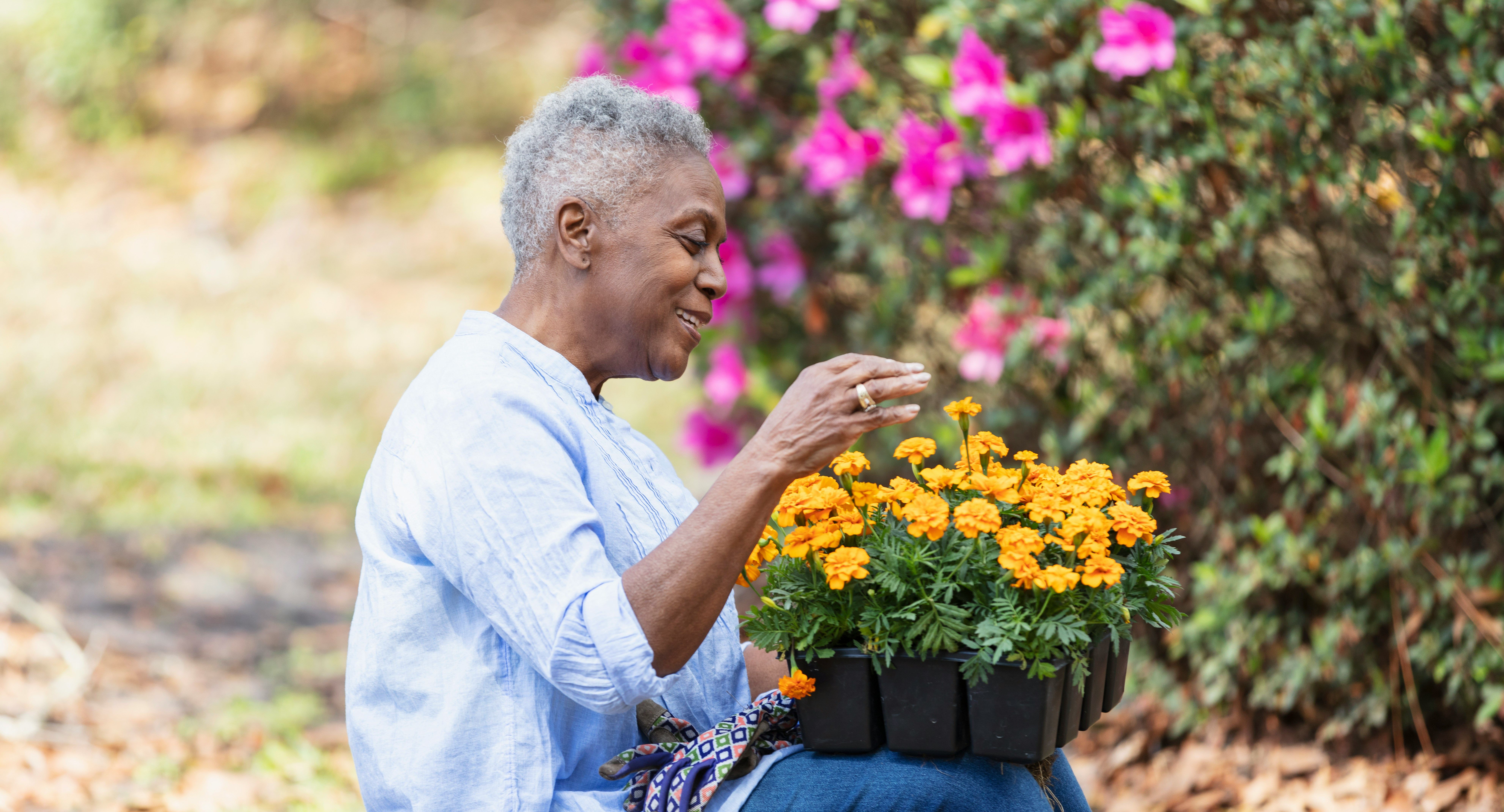 An elder Black woman tending flowers in her garden